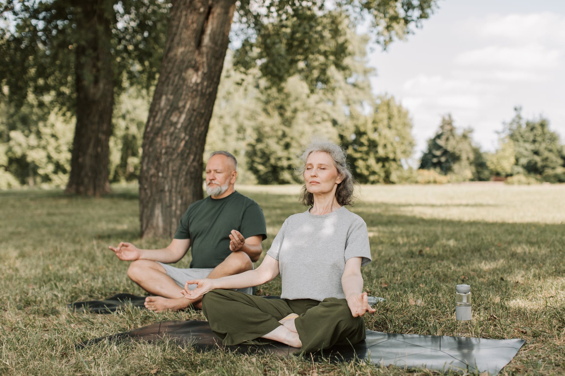 an elderly couple meditating in the park